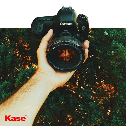 A hand holds a Kase-branded camera in a natural setting, demonstrating Kase photography equipment’s outdoor use.