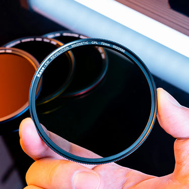 Holding a camera lens filter with the brand logo "Kase"