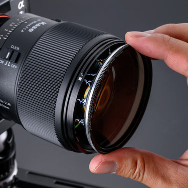 Camera lens with a hand adjusting it on a dark background