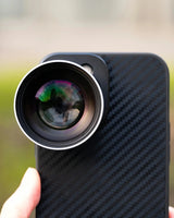 Phone case with a lens attachment held by a hand against a blurred background